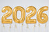 Gold '2026' balloons against a white wall